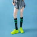 Detailed view of knee-high compression sports socks featuring striped design for leg support. - Mid-Calf Black with Green Stripes