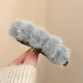 Detailed close-up of a soft grey plush hair claw clip with a fluffy furry texture. - Gray