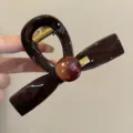 Primo piano dettagliato della graziosa molletta marrone con texture lucida e perla. - Piccolo (8cm) / Molla per Capelli Perla Etichetta Dorata