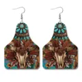 Detailopname van westerse vintage lederen oorbellen met unieke schedel en turquoise print. - Stierenschedel Veer Turquoise Koeienlabel Stijl