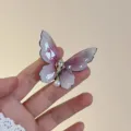 Close-up detail of the elegant gradient butterfly hair clip with dazzling rhinestones and pearl. - Pink