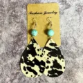 Gros plan de boucles d'oreilles pendantes en cuir imprimé vaches avec perle de turquoise. - Cuir à Pois Marron (8)