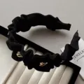 Detailansicht eines eleganten schwarzen Rüschen-Haarreifs mit goldenen Herzakzenten für Damen. - Herz Plissierter Haarreif / Schwarz