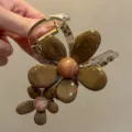 Closeup detail view of brown resin flower hair claw clip, elegant floral hairpin for women. - Coffee