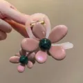 Close-up detail of the floral hair claw clip, featuring pink resin petals and green center. - Pink