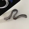 Detail shot of the minimalist metal hair claw clip, featuring a unique abstract line design for thick hair. - Gunmetal