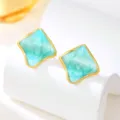 Nahaufnahme von geometrischen türkisen Emailleschmuck Ohrringen mit elegantem Goldrand. - Blaugrün