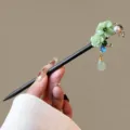 Close-up detail shot of vintage wooden hair stick with green floral and tassel decor. - Jingyequan Style (FZ25115)