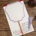 Traditional Chinese silk round fan detail close-up with wooden handle and purple tassel. - Beechwood Flying Immortal Pattern - Purple Border