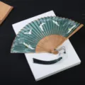 Éventail pliant de style chinois avec motif de grue, manche en bambou et pompon pour Hanfu. - Vert grue du Japon