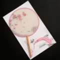 Traditional Chinese round fan with pink magnolia floral design, wooden handle and tassel. - New - Splendid Golden