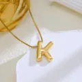 Gros plan du collier avec pendentif lettre K gonflée dorée et sa texture métallique brillante. - Or-Lettre K