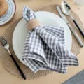 Detail view of the cotton plaid cloth napkin with a rustic jute ring, perfect for kitchen table decor. - 18x18 Inch / Gray