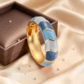 Dettaglio ravvicinato del bracciale aperto in lega con smalto blu e dettagli geometrici dorati. - Sfumatura blu
