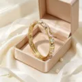 Squisito bracciale rigido retrò dorato con fiori in smalto e strass, vista di dettaglio. - Rosa + Bianco