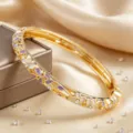 Bracciale rigido dorato con cerniera decorato con fiori in smalto viola e cristalli scintillanti. - Bianco + Viola