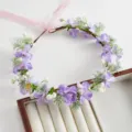 Primo piano dettagliato di una corona di fiori viola con nastri rosa e foglie verdi per sposa. - Viola
