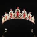 Primo piano dettagliato di una corona dorata scintillante con gemme rosse e strass. - Oro + Strass Rosso
