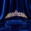 Primo piano dettagliato di una tiara dorata con cristalli viola scintillanti e strass trasparenti. - Oro con strass viola