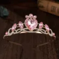 Primo piano di una tiara dorata per bambini con strass rosa a cuore e taglio marquise. - Stile Strass Rosa Oro