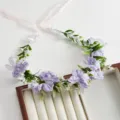 Dettaglio della fascia floreale da sposa con fiori artificiali viola e nastri rosa. - Viola