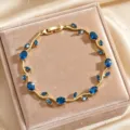 Detailed close-up of a chic gold-plated vine bracelet adorned with sparkling blue cubic zirconia. - Sapphire Blue