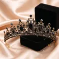 Primo piano dettagliato di una lussuosa tiara di cristallo nero e corona d'oro su raso. - Oro Antico + Strass Completamente Neri