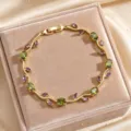 Exquisite gold-toned branch design bracelet featuring vibrant green and purple cubic zirconia stones. - Green & Purple