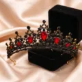 Primo piano dettaglio della tiara di cristallo nero e oro vintage con pietre rosse brillanti. - Oro Antico + Strass Rosso
