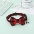 Detailed view of a red and black plaid pet collar with a bow tie and silver bell - Red