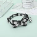 Close-up of black and white checkered pet collar with a bell and decorative bow detail - Gray