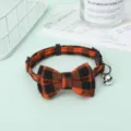 Detailed close-up view of the orange and black plaid pet collar with a bow and bell - Orange