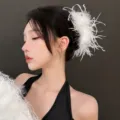 Detailed close-up of white ostrich feather hair claw clip worn on side, soft texture and chic style. - White