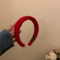 Gedetailleerd overzicht van de rode gebreide haarband, zachte geribbelde textuur en kwaliteit. - Rood