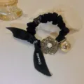 Chouchou de cheveux en tissu noir avec pendentif camélia en strass et boule dorée. - Accessoires camélia perles et strass
