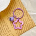 Close-up view of a purple star-shaped acrylic keychain with a matching small bell and ring - Purple Star Keychain