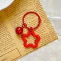 Detailed view of red star-shaped acrylic keychain with a matching red bell charm - Red Star Keychain