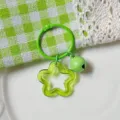 Green acrylic star keychain with a matching bell and heart cutout on a lace background. - Transparent Green Star Keychain