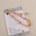 Handgemaakte oranje gevlochten telefoonbedel sleutelhanger met metalen kralen en sterren. - Oranje