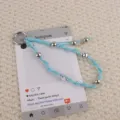 Handgemaakte gevlochten blauwe waskoord sleutelhanger en telefoonbedel met metalen kralen. - Blauw