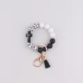 Silicone beaded keychain bracelet in black and white with cross charm and PU tassel. - Black