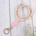 Detailansicht der Holzketten-Schlüsselanhänger mit rosa Silikon-Gänseblümchen und Ring. - Rosa