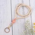 Nahaufnahme der Holzperlen Schlüsselanhänger mit rosa Silikon Gänseblümchen Anhänger. - Pfirsichrot