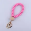 Pink silicone beaded wristlet keychain detail showing smooth flat beads and wooden accent. - Rose Red