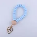 Silicone beaded keychain detail, light blue flat beads with large wooden bead and gold hardware. - Blue
