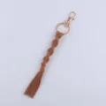 Handmade woven cotton rope keychain with gold metal hardware and stylish tassel charm accessory. - Caramel color