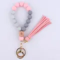 Detail view of silicone bead wristlet keychain with wooden charm and pink tassel pendant. - Pink