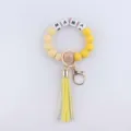 Silicone bead wristlet keychain with yellow tassel and letter beads detail view showcase. - Yellow