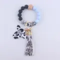 Detail shot of the silicone bead wristlet keychain with cow head charm and tassel. - Light Blue