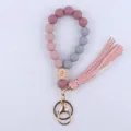 Close-up view of silicone bead wristlet keychain with wooden eye charm and pink tassel. - Deep Bean Paste